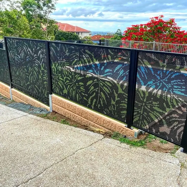 Black PoolPerf panels with the Monstera leaf design stepping down beside a sloping driveway, the pool visible through them